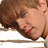 Pixelated close-up of a person's face with closed eyes, brown hair, and visible red mark on the cheek against light background.