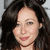 A pixelated close-up of a person with long dark hair, light skin, and a neutral expression, cropped to show the head and upper shoulders against a light background.