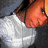 Pixelated image of a person in profile wearing a white shirt against a gray background, with orange text reading "shatie" and "ari" on the right side.