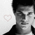 Black-and-white pixelated image of a person with dark hair wearing a dark jacket over a light shirt, with a faint pink heart symbol on the left side.