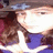 Pixelated static image of a figure in dark clothing holding a white object against a blurred background with purple and brown tones.