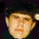 Animated sequence of a person wearing a dark cap with a small circular emblem, showing multiple facial expressions and head rotations against a dark background.