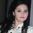 Pixelated static image of a person with long dark hair wearing a white top with dark accents, set against a dark background.
