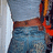 Pixelated static image showing a partial figure with blue and red elements against a light background.