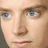 Pixelated close-up of a person's face with blue eyes on left, blue background with white text on right.