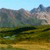Pixelated landscape with layered mountains under a light blue sky, green and brown terrain, and a dark horizontal band across the middle.