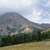 Pixelated landscape with mountain, trees, and sky in muted tones.