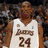 Two basketball players in action, one wearing a white Lakers jersey with number 24 and the other in a purple jersey shooting a ball.