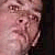 Pixelated close-up of a person's face with light skin tone, visible eyes, nose, and mouth, and dark hair on the right side.