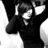Black-and-white animated icon shows a person with dark hair wearing a dark top, hands raised near head in a gesture, against a light background with dark shapes.