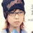Pixelated close-up of a person wearing dark blue headwear with pink accents, light blue clothing, and long brown hair styled in two braids.