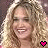 Two side-by-side pixelated frames of a woman with long curly blonde hair smiling, each featuring a pink heart symbol at the bottom right corner.