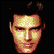 Pixelated static image of a human face with dark hair against black background, rendered in warm tones with visible dithering and pixelation artifacts.