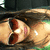 A pixelated image shows a person with dark hair lying down, wearing red clothing and pink earrings against a blurred background.