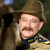 Pixelated image of a person wearing a brown hat and dark jacket, holding a phone to their ear with a neutral expression.