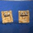 Two square pixelated icons with textured beige faces on blue background, one with a straight mouth, the other with a curved mouth, side-by-side.