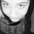 Pixelated grayscale close-up of a person's face with dark hair, neutral expression, and visible eyes and mouth.