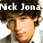 Pixelated image of a person with dark curly hair wearing a light-colored jacket over a dark shirt, with white text reading "Nck Jona" above the head.