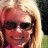 Pixelated close-up of a person with light brown hair, dark sunglasses, and a pink garment against a blurred background.