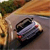 Pixelated image of a vehicle on a road with blurred background elements including greenery and orange-brown tones.