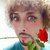 Pixelated portrait of a person with brown hair holding a red rose, wearing a blue garment against a light background.