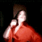 A person in a red satin shirt performs various hand gestures and facial expressions against dark backgrounds.