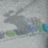 Pixelated static image with muted gray background and scattered green, blue, and brown pixel clusters forming indistinct shapes.