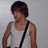 Pixelated image of a person with short dark hair wearing a white tank top and black strap across chest against light gray background.