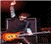 Pixelated image of a person playing a guitar with raised arm, red text reading KEVIN QUINN GUITARIST on black background.