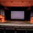 Static image of a dark interior with a central rectangular screen framed by orange-brown architectural elements and a lower horizontal band.