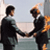 Animated contact sheet showing two men in business suits shaking hands with orange flame effects on the right side, displayed across three frames in a 2x2 grid layout.