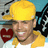 Pixelated image of a person wearing a yellow cap and shirt, holding a red heart-shaped object with a white horizontal line, against a blue and gray background.