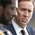 Static pixelated image of a person in a dark suit and white shirt with a black tie, partially cropped on the left side.