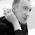 Black-and-white pixelated image of a person with short hair wearing a dark jacket over a light shirt, facing right with a neutral expression.