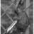 A grayscale pixelated image shows a sword-like object with a bright white blade and dark hilt against an abstract background of varying gray tones.