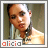 Alicia Keys in a pixelated portrait with light brown skin, dark hair pulled back, and a white top with a black choker, her head slightly tilted left.