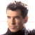 Pixelated static image of a man's face and upper shoulders in profile view with dark hair, wearing a black turtleneck shirt against a white background.