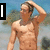 A shirtless man with short brown hair stands outdoors, hand on head, against a blurred background with trees and sky.