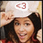 A pixelated image shows a person with long dark hair wearing red clothing, holding up a white sign with pink text '<3' against a light background.