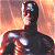 Pixelated figure in dark suit with silver chest and head accents, standing against warm-toned gradient background.