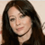 A static pixelated image of a person with long dark hair, light skin, and a neutral expression, wearing a dark top against a light background.