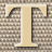A static pixelated image of a large light brown letter T with dark brown outlines against a checkered background.