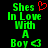 Green pixelated text reads "Shes In Love With A Boy" with a red heart above "Shes" and a green heart below "Boy" on a black background.