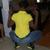 A person in a yellow shirt and blue pants crouches with arms raised, viewed from behind in a pixelated animation.