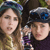 Two people in close proximity, one wearing a blue and green cap, the other in a dark cap with blue accents, both with neutral expressions against a blurred background.