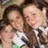Two people in close physical proximity with one person's arm around the other, both facing forward against a blurred background.