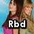 Two women in casual clothing stand against a blue background with white lines; text overlays read "Rbd", "dulce-", and "rebelde".