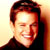 Static pixelated image of a person's face with dark hair and light skin, wearing a dark top against a gradient background transitioning from yellow to orange.