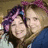 Two people with purple hair accessories pose closely together in a photo, surrounded by red and gray text on a