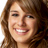 Pixelated close-up of a person with light brown hair and fair skin smiling broadly, showing teeth against a white background.